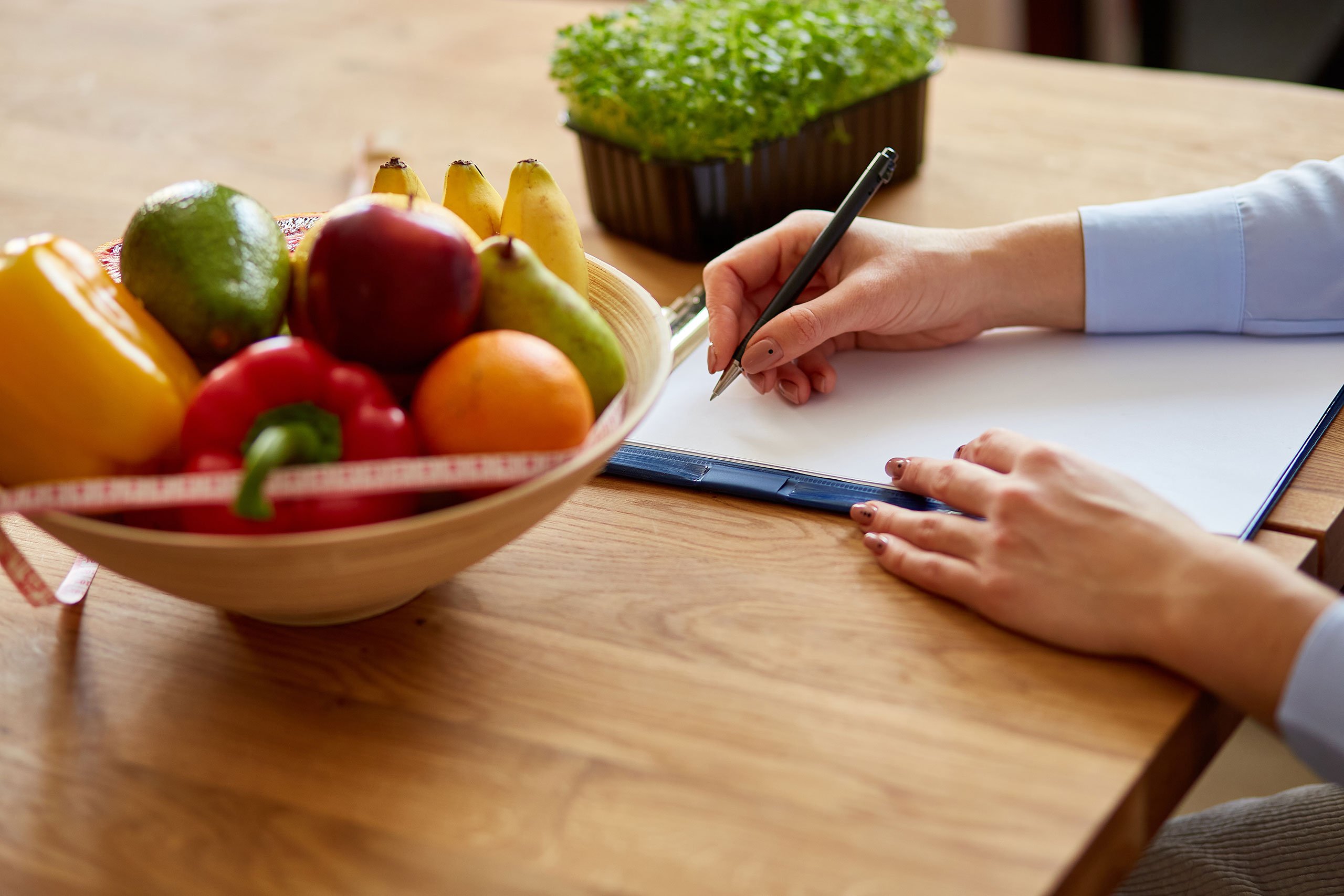 Nutritionist, dietitian woman writing a diet plan, with healthy vegetables and fruits