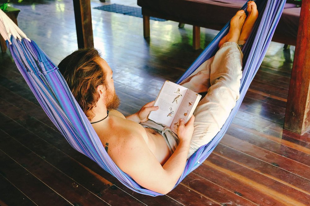 man reading a book in a hammock at the punta mona retreat center